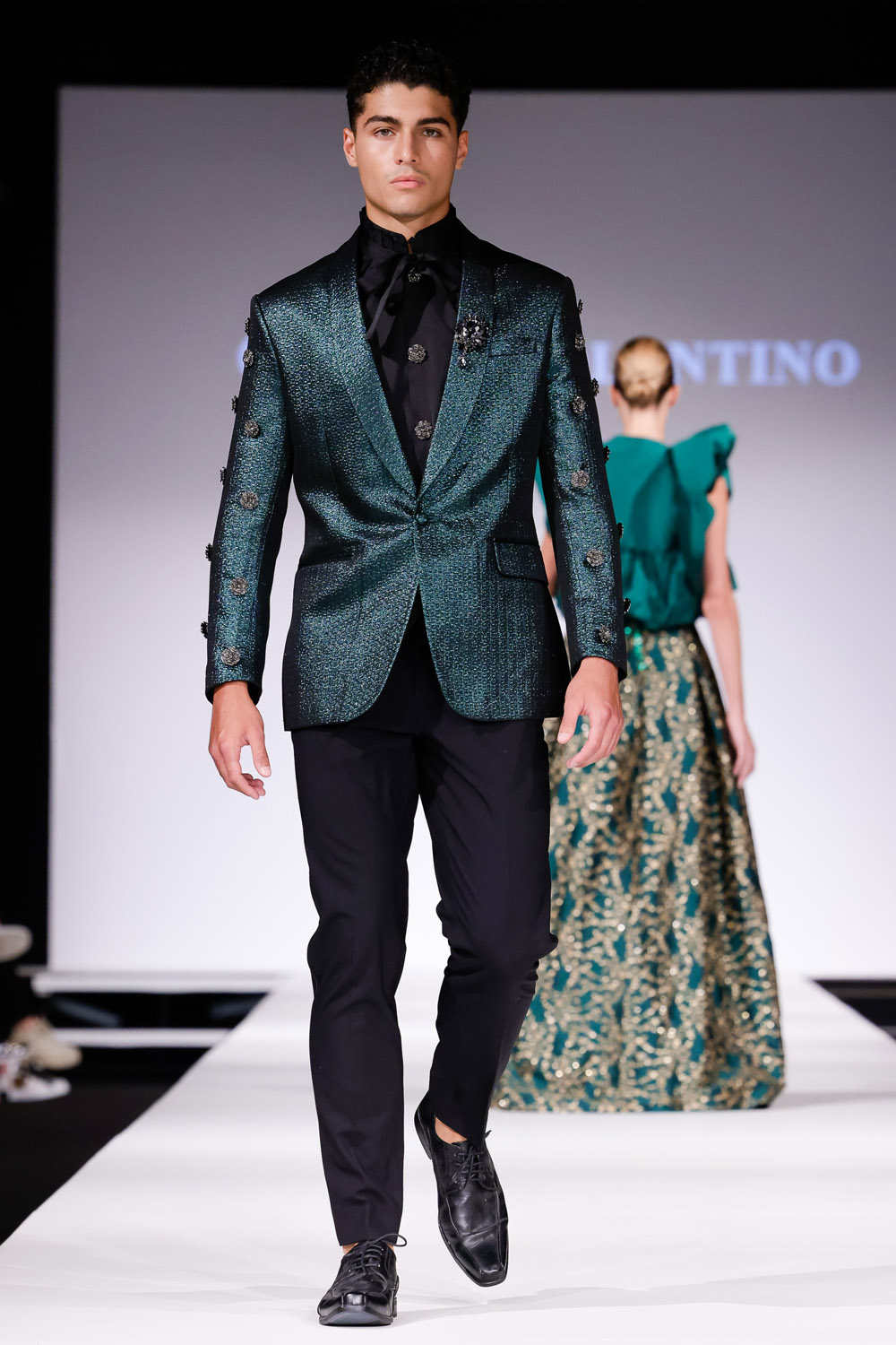 Green brocade suit jacket, black shirt and black pants