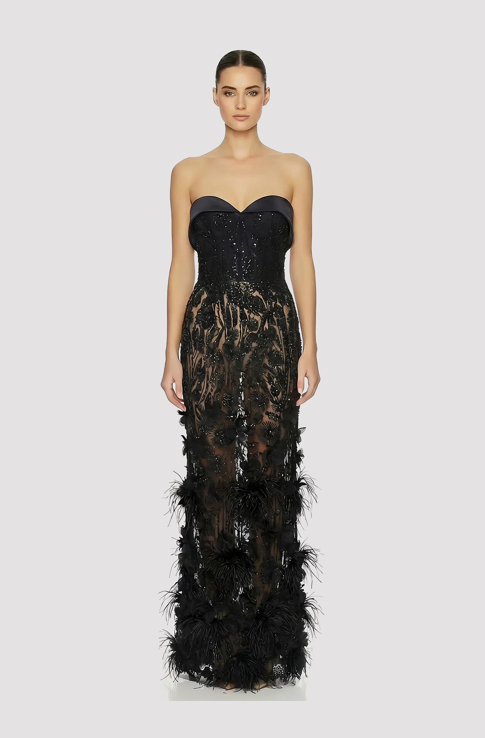 Front view of a woman in a Black corseted sheer column couture gown with a beaded bodice and skirt embellished with 3D floral appliqués and ostrich feathers 49, image 1